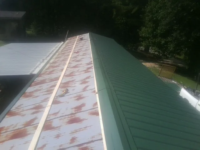 Old rusted panels beside newly installed green metal roofing — Wind Damage Roof Repair by Roofing Brothers in Minor Hill