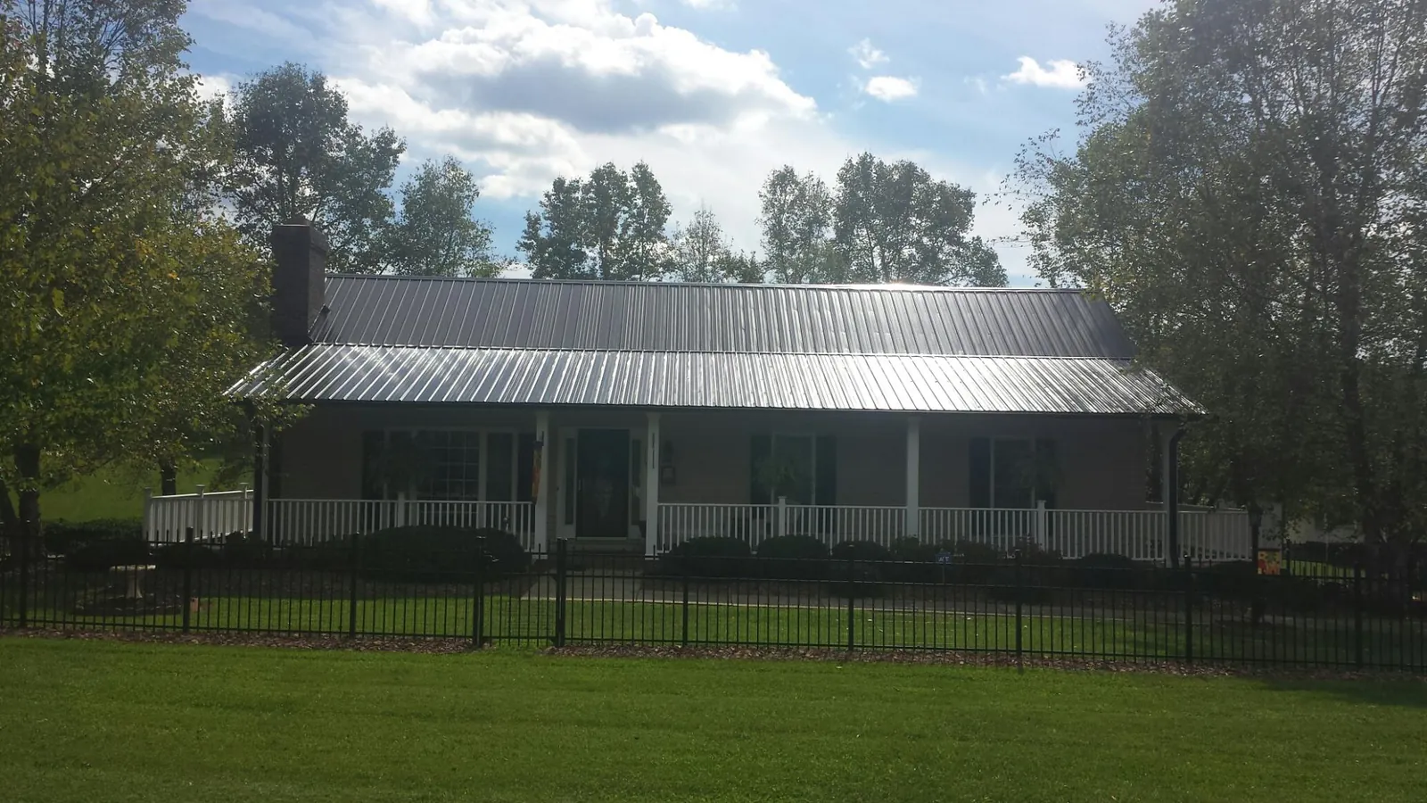 Gray metal roof on a brick ranch with a full width front porch — Gutter Guard Installation work by our crew in Minor Hill