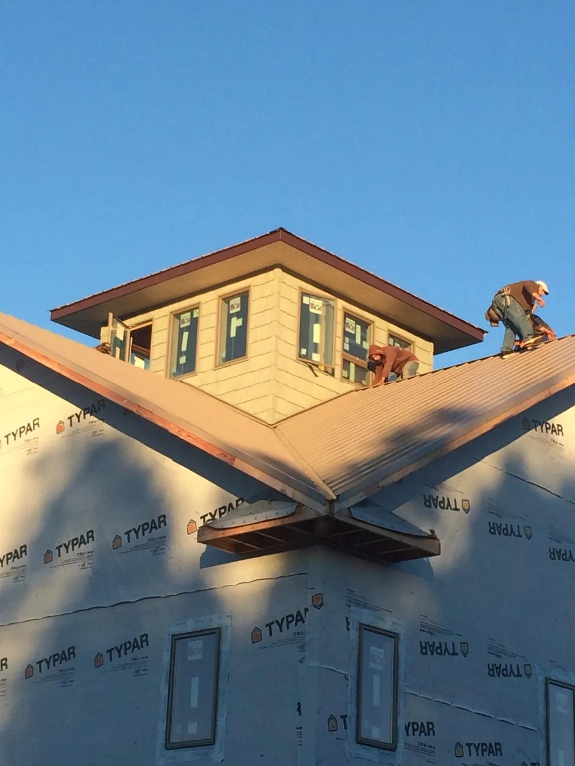 Roofers working around a rooftop cupola on a new metal roof at sunset — Roof Waterproofing in Minor Hill by Roofing Brothers